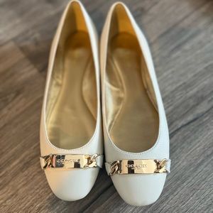 White leather coach slip on flats with brass tag.